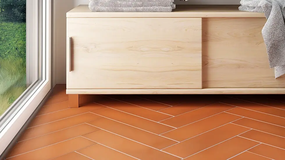 Wooden cabinet with silver sink, beige towels, black bottle, and plants on countertop. Terracotta herringbone tiles. Green view outside.