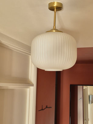 ZOOMED VIEW ONTO REEDED GLASS MODERN PENDANT IN HALLWAY WITH TERRACOTTA BOX IN BACKGROUND