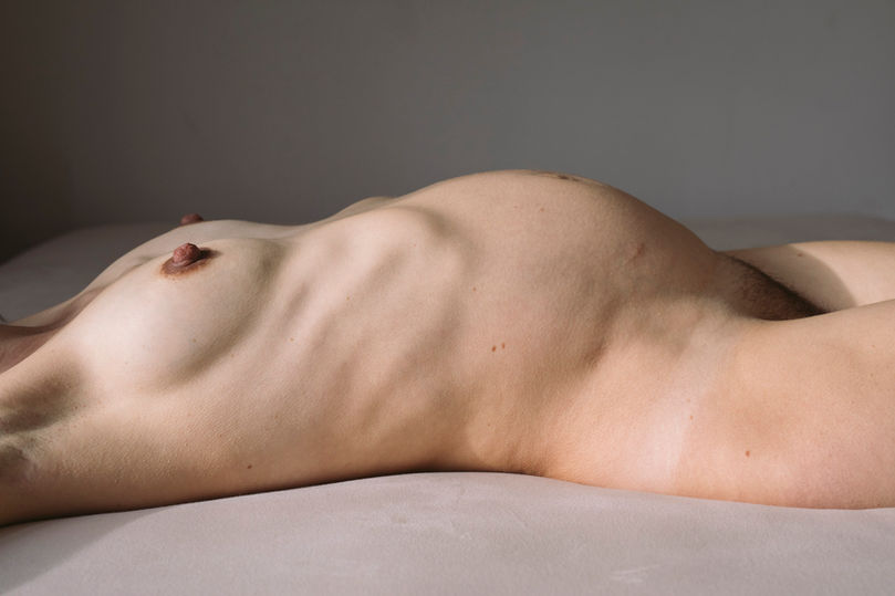 ausgestreckter schwangerer Körper im Bett