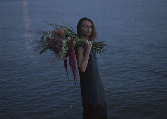 Portrait eines jungen Frau am Wasser mit Blumenstrauß