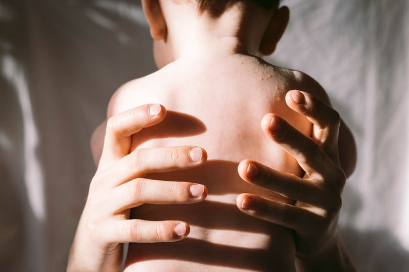 Männerhände halten Baby im Sonnenlicht