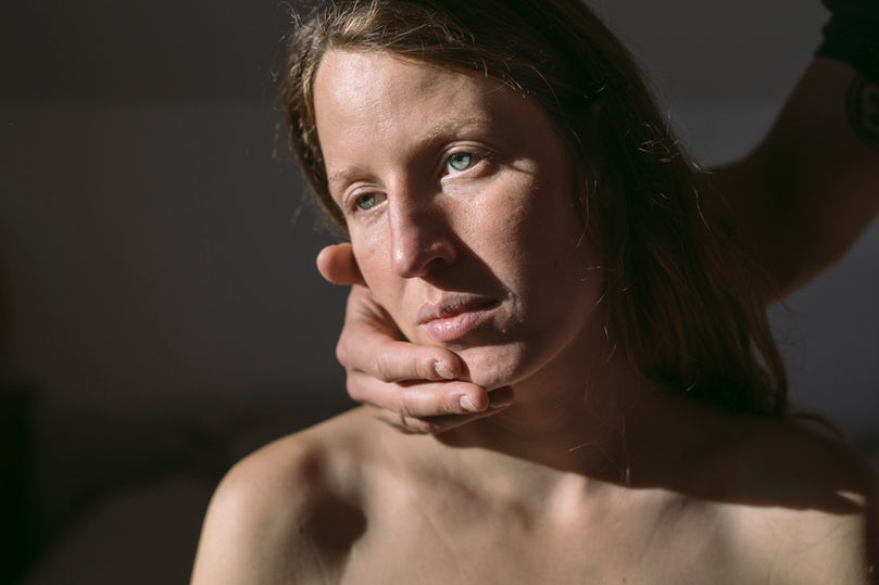 Portrait einer Mutter im Sonnenlicht mit männlicher Hand, die das Gesicht umfasst