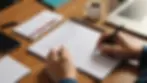 Close-up view of a notepad and pen on a table with a family testing a communication strategy