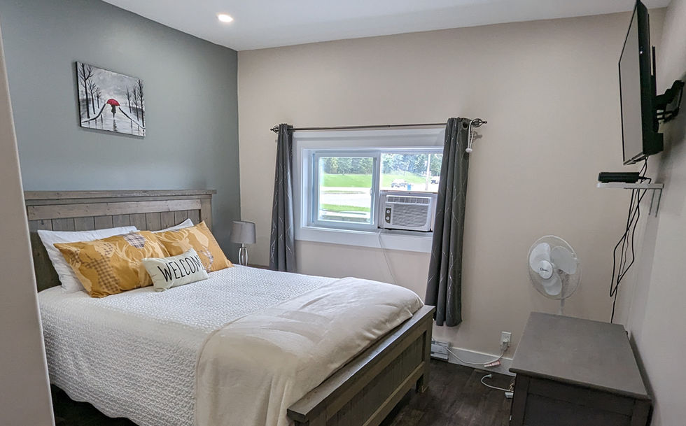 queen size bed with yellow pillows and white bed spread, desk and tV