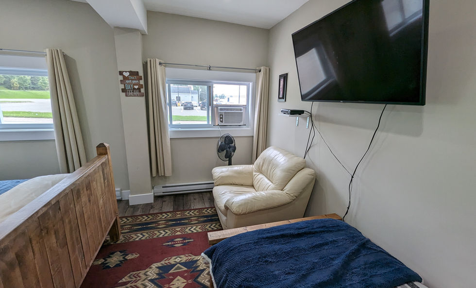 Trailway Hub Signal Hill Room single bed with dark blue blanket and big comfy light leather chair