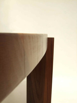 Gros plan sur le profil de la table montrant la manière dont les pieds massifs se fondent artistiquement dans la structure, créant un attrait esthétique distinctif. Une création d'Isabelle Pillet, designer ébéniste, Kervignac, Lorient, Morbihan, Bretagne.