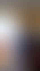 drewniana komoda w przedpokoju, nad którą znajduje się kolaż zdjęć, oraz świętych obrazków na tle żółto-niebieskiej ściany.