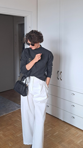 dziewczyna w białych spodniach i szarym swetrze z golfem