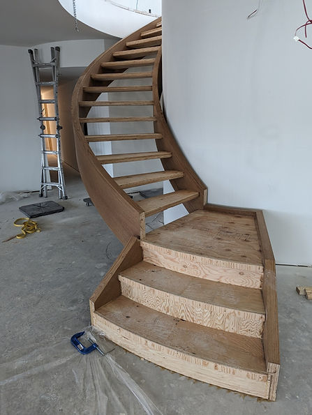 A finished wood staircase being installed in a new home.