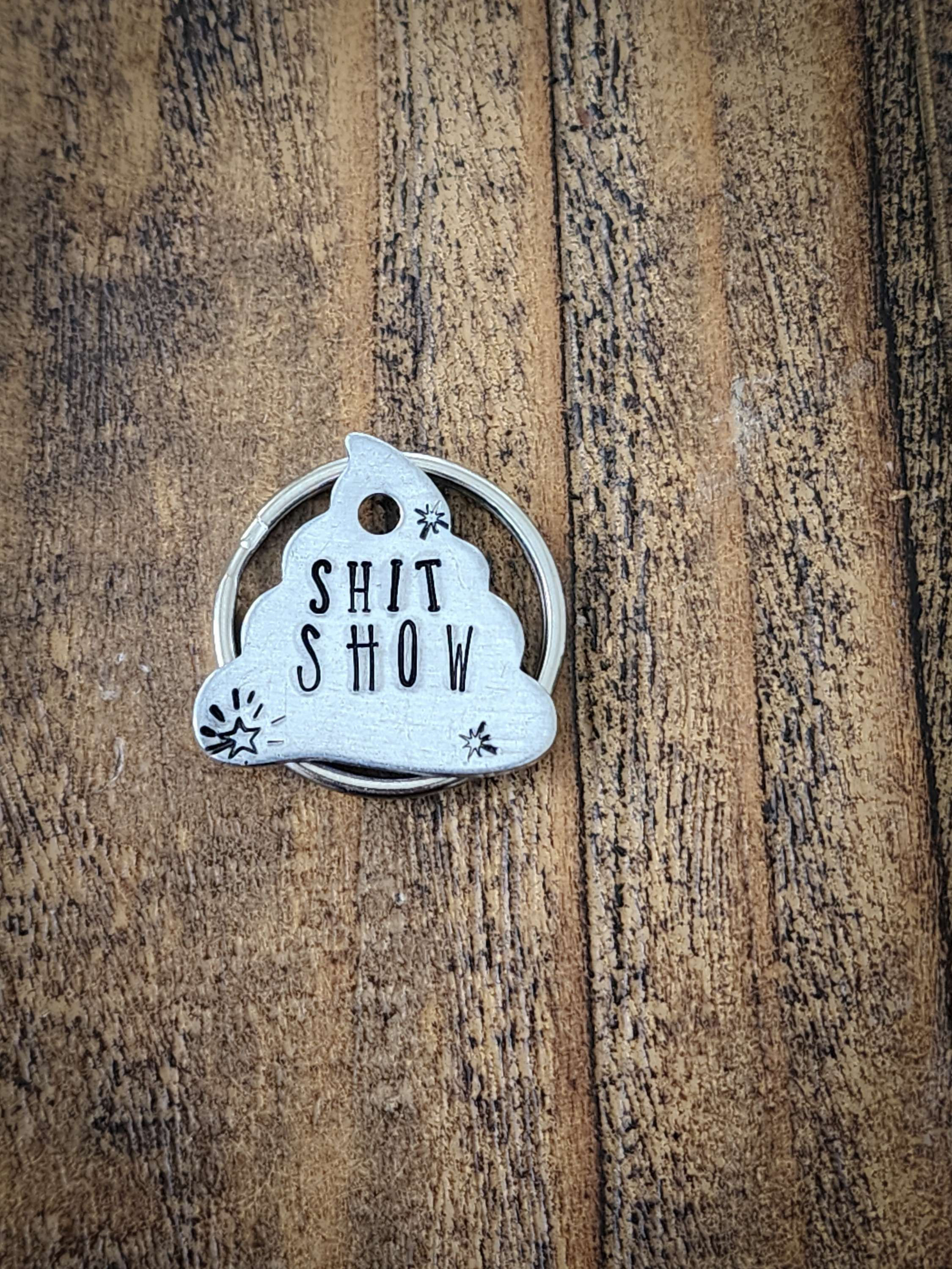 Poop emoji shaped dog tag that says "Shit Show"