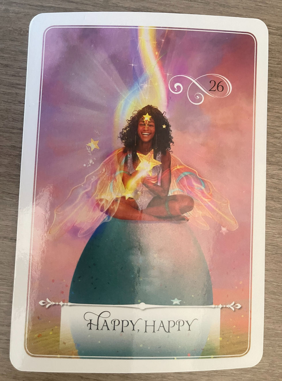 Woman sitting on a colorful sphere, smiling with star motifs around. Background is ethereal with vibrant colors. Text: "Happy, Happy".