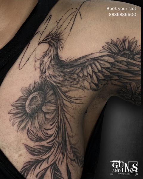 Close-up of a phoenix shoulder tattoo with sunflower detail in black and grey at Guns and Inks in Hyderabad.