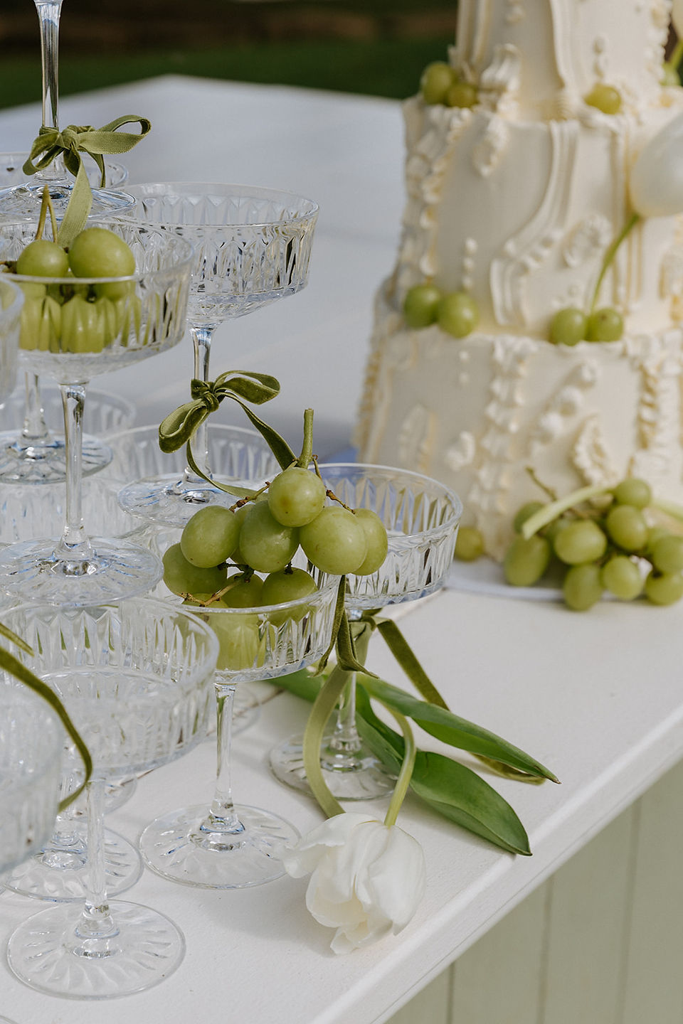 Green grapes in elegant glassware with wedding cake in background