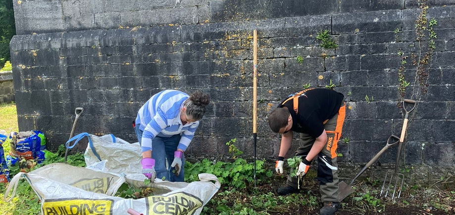 Two volunteers work hard removing weeds from near the Mansion House