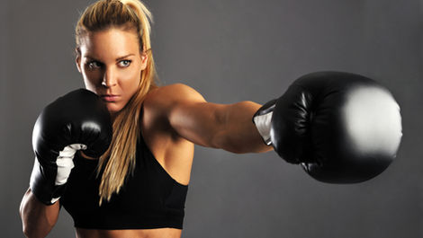 Boxerin mit schwarzen Handschuhen und schwarzem Top am Schlagen