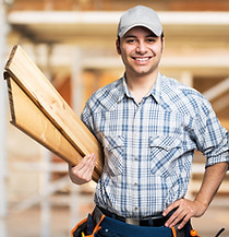 Portrait of a smiling carpenter holding wood planks in a construction site.jpg