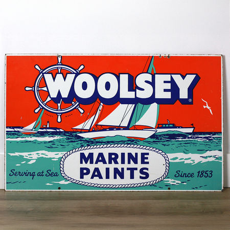 Orange and teal Woolsey Marine Paints porcelain sign with ship's wheel logo, sailboats, and Serving at Sea Since 1853
