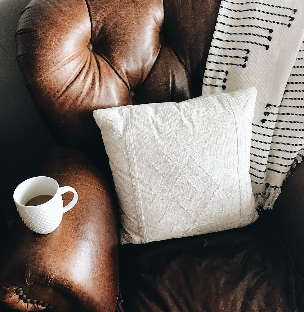 Soft worn leather sofa with coffee cup and soft throw. Perfect spot to curl up and read a book.
