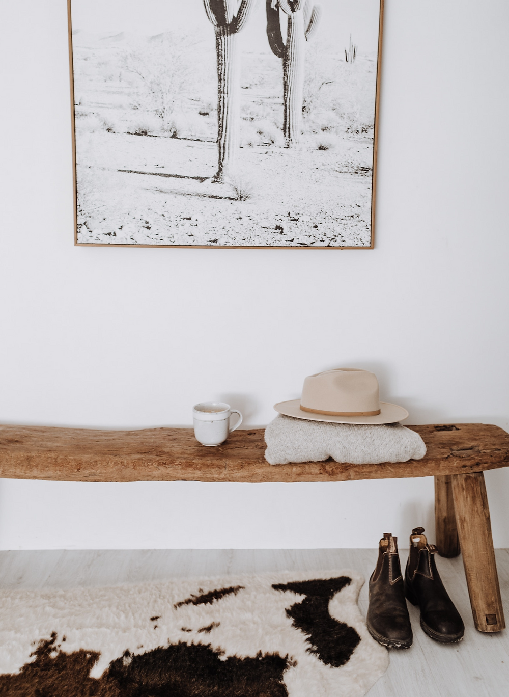 Modern rustic boho neutral home with white walls and raw wooden bench.
