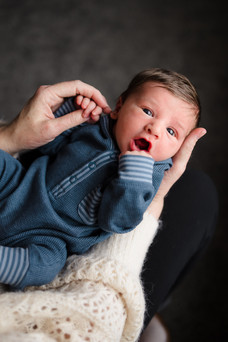 newborn boy yawning on mothers lap