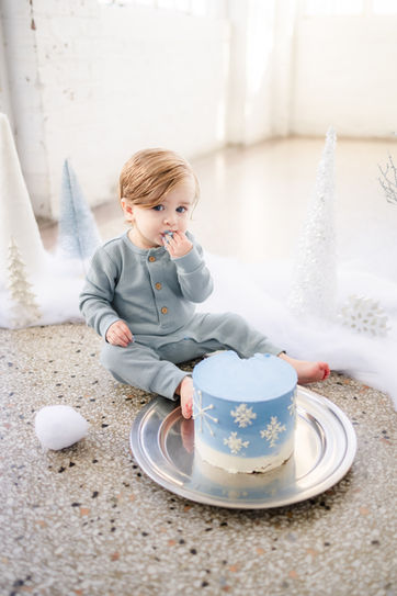 winter 1 year cake smash milestone snowflake theme photo of baby boy in a white room at the bleak house in knoxville tn / photo by knoxville maternity and newborn photographer wood shutter photography / see more at woodshutterphotography.com