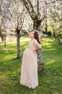 expecting mother poses in blooming trees in the spring at knoxville botanical gardens during Knoxville TN maternity portrait session photo by Knoxville maternity, newborn, and family photographer Wood Shutter Photography