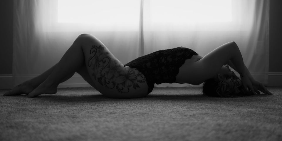 black lace lingerie teddy bodysuit / black and white boudoir pose laying on floor in front of a window during knoxville boudoir photo session / knoxville bridal boudoir photography / photo by knoxville boudoir photographer rosewood boudoir / see more at rosewoodboudoir.com