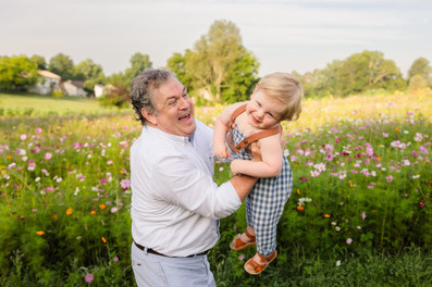 dad playing with young son in front of wildflowers