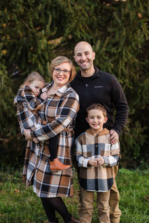 family of four in the winter in front of evergreens at knoxville botanical gardens during Knoxville TN maternity portrait session photo by Knoxville maternity, newborn, and family photographer Wood Shutter Photography