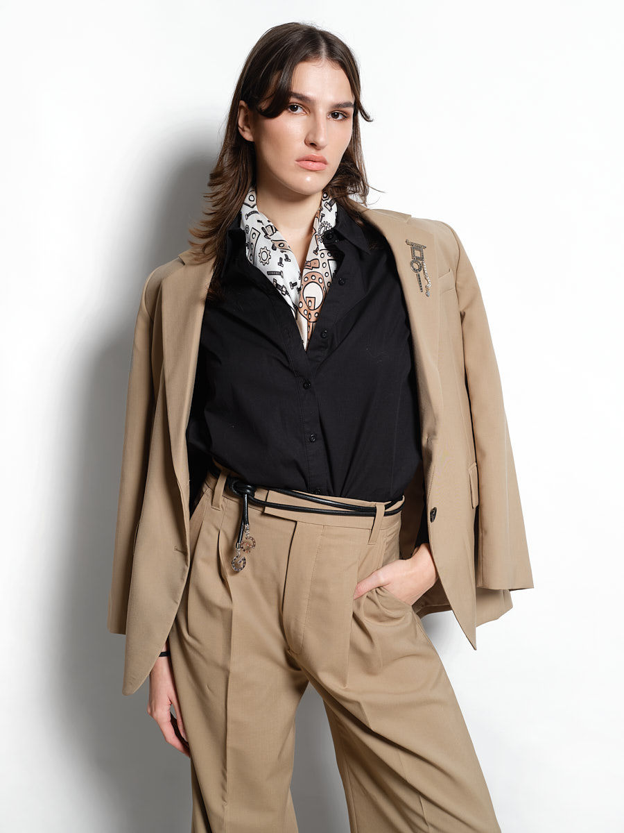 Thumbnail: žena v béžovém saku s broží