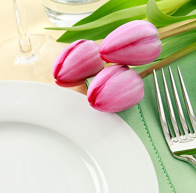 Three pink tulips grace a table setting