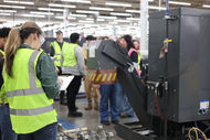 Student holding a clipboard in manufacturing facility