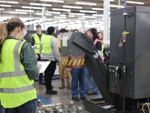 Student holding a clipboard in manufacturing facility