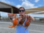 woman holding three crabs outdoors