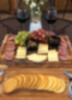 charcuterie board with cheese, meat, and grapes and two glasses of wine