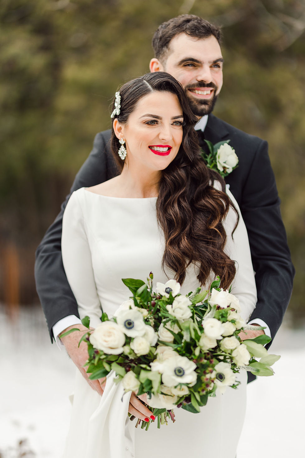 bride and groom posing outside in their wedding attire smiling off to the side. bride is holding an all white floral bouquet. all via unmeasured events
