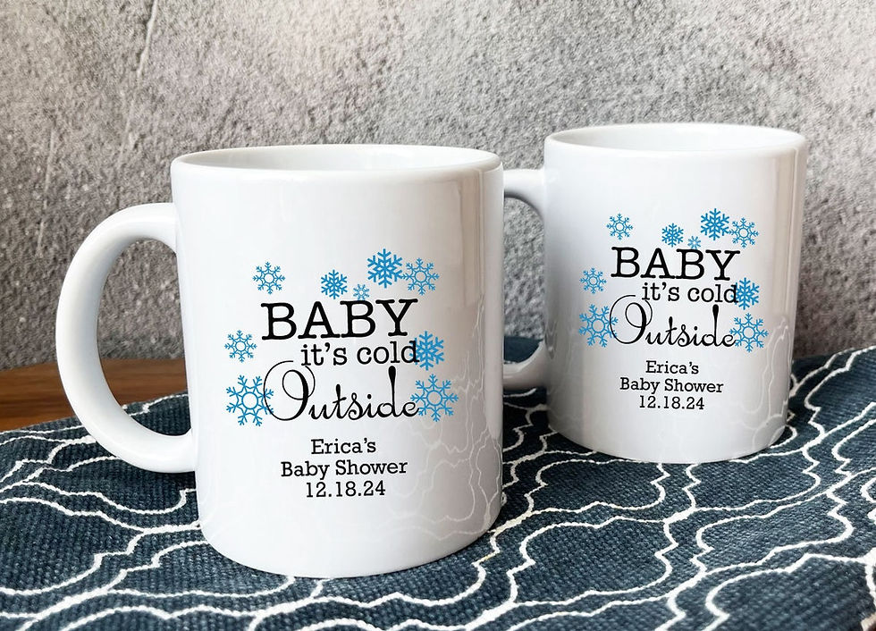 two white mugs with blue snowflakes and "baby it's cold outside" w/ name and date of someone's baby shower on a tan placemat. all via unmeasured events