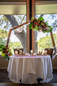 wedding reception table with "mr.and mrs." in wood infront of a boho floral arch. all via unmeasured events