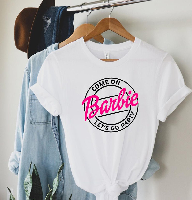 white "come on barbie, let's go party" shirt hanging up on a closet rack. All via unmeasured events