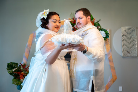 bride and groom holding up their wedding rings on a white pillow at the top of their alter. all via unmeasured events