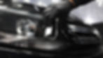 A hand in black glove wiping car's headlight, detail Apex Mobile Shine service.