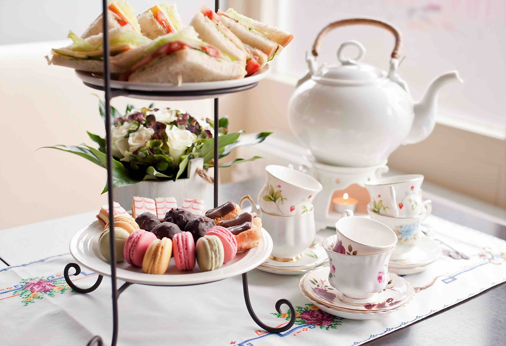 High tea, with sandwiches, cakes and a pot of tea.