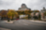 Street in Quebec City with autumn trees, historic buildings, and a prominent castle atop a hill. Overcast sky. Empty road with traffic signs.