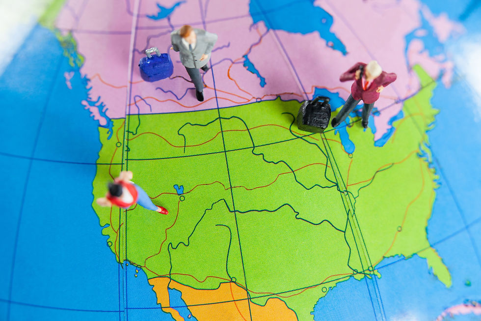 Miniature figures with suitcases stand on a colorful map of North America. Background shows vibrant map details.