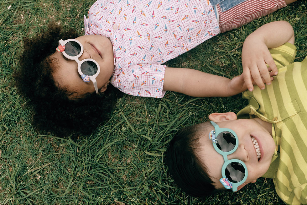 Niños cogidos de la mano sonriendo tumbados en el césped