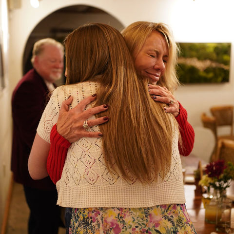 Two women, one donor and one staff member and survivor, hugging at a nonprofit ministry event.