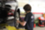Mechanic conducts a New York State vehicle inspection, ensuring compliance and safety standards in the workshop.