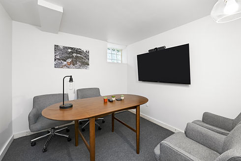 Ground floor conference room. There is a 4-5 person conference room table, 4 comfy chairs, and a tv with camera for meetings