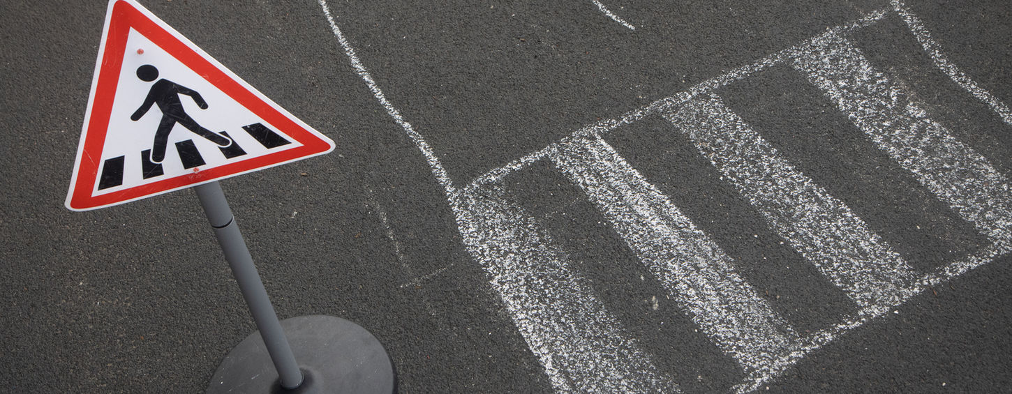 Pedestrian crossing sign on asphalt with a painted crosswalk, safety concept.
