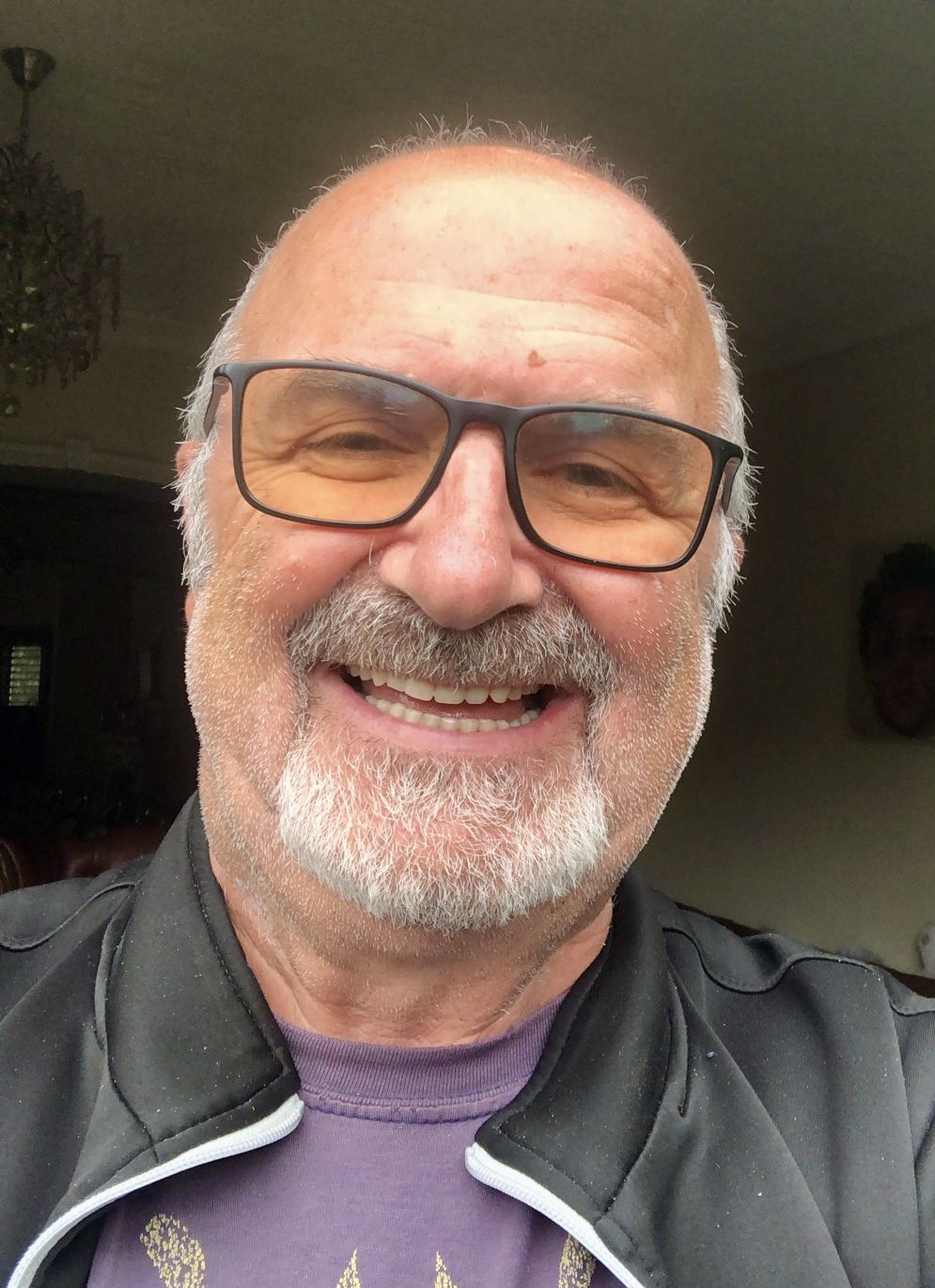 Smiling man wearing glasses and a black jacket posing for the camera